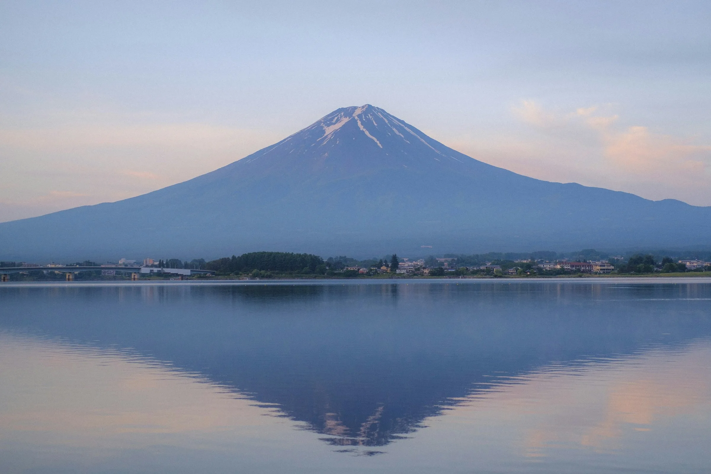 Snow-capped Mount Fuji seen across a lake from an established viewpoint